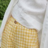A decorative button of yellow gingham linen trousers