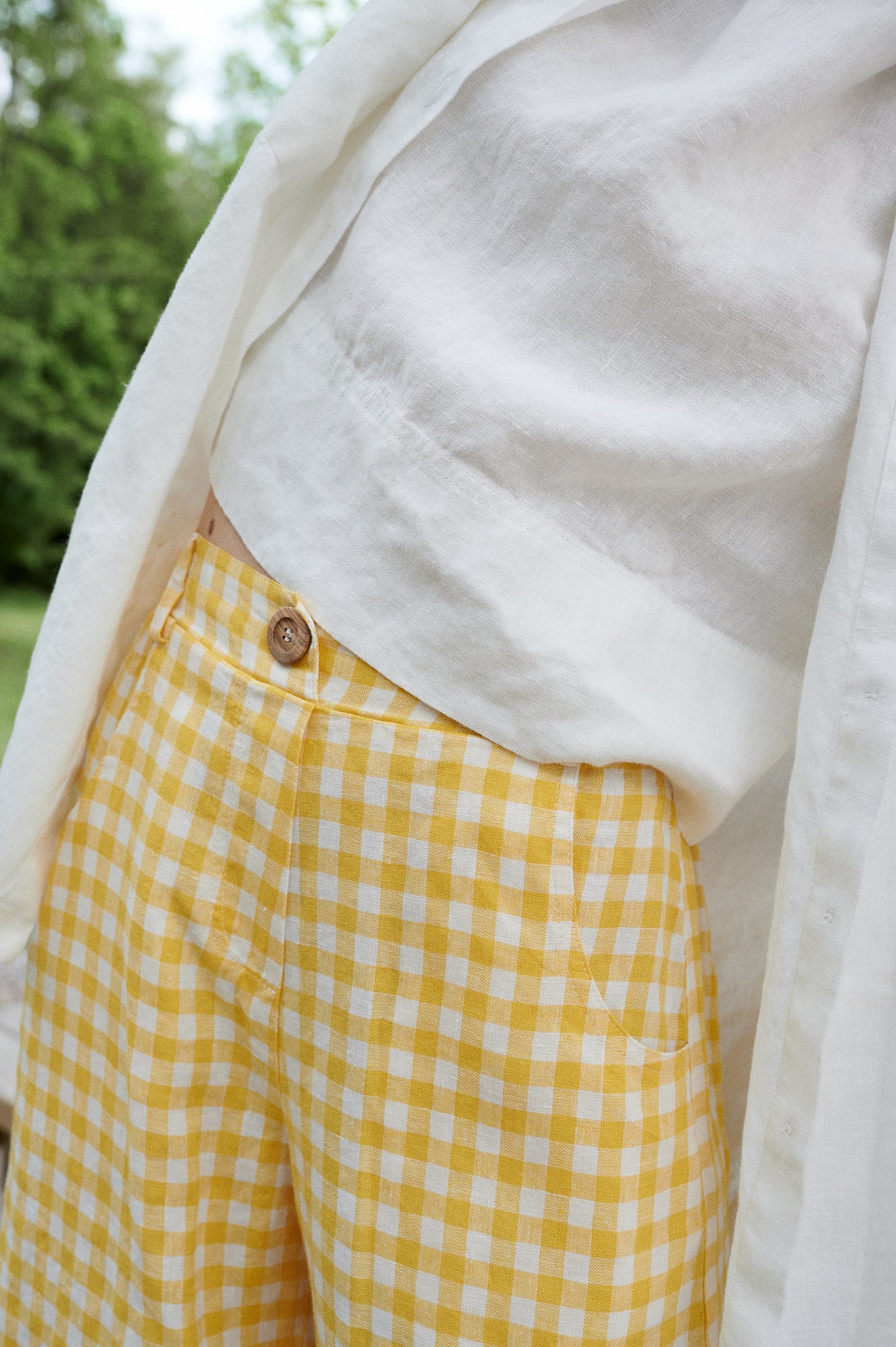 A decorative button of yellow gingham linen trousers