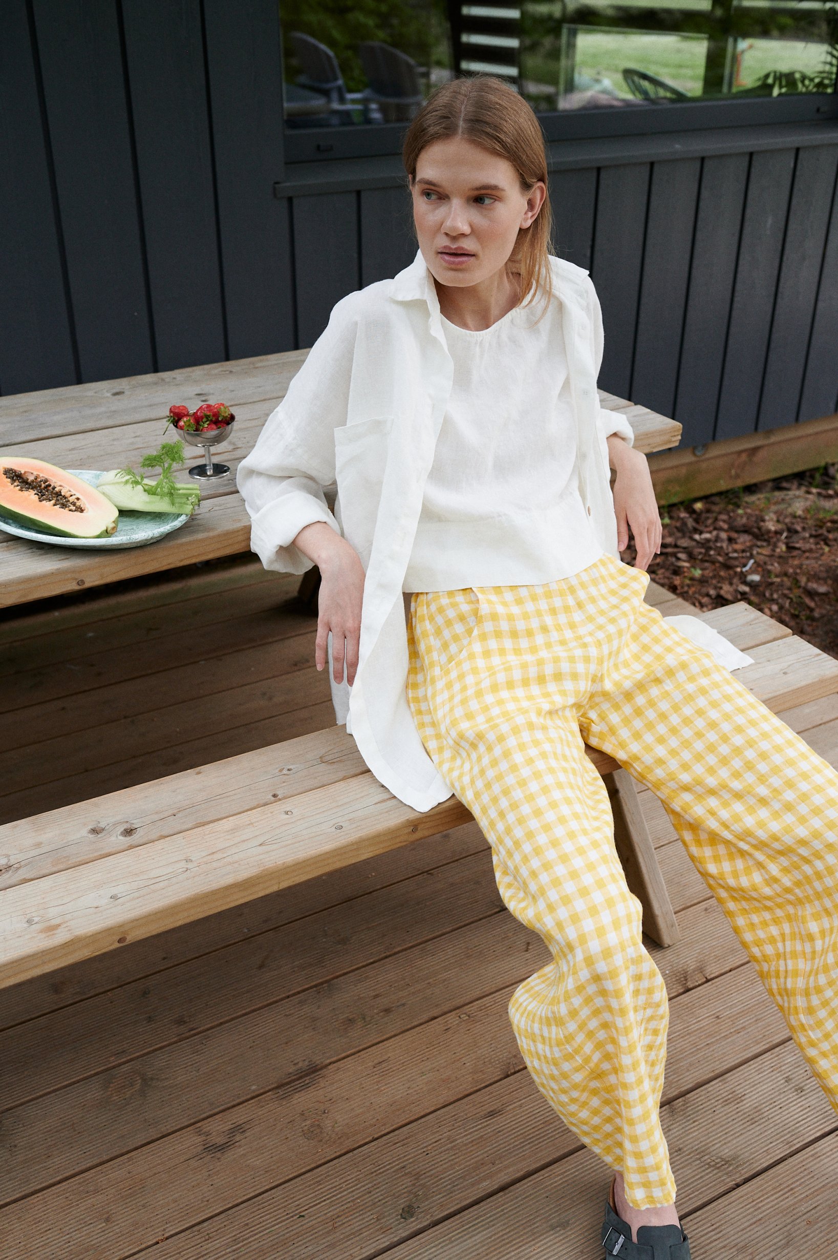 A model sitting in linen high waisted linen trousers in yellow gingham