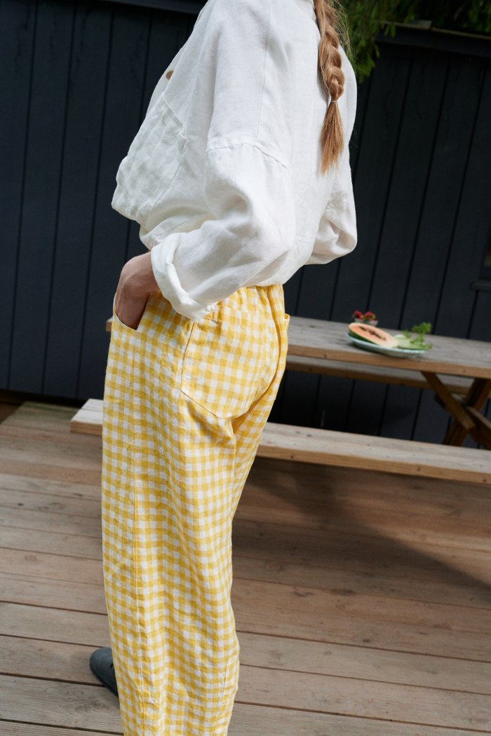 A woman in high waisted linen barrel trousers in gingham linen
