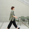 A woman walking in oversized linen green shirt