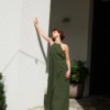A maxi forest green linen dress with a halter neck and an overlapping skirt