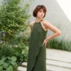 Model posing in a long forest green linen dress with an asymmetrical seam
