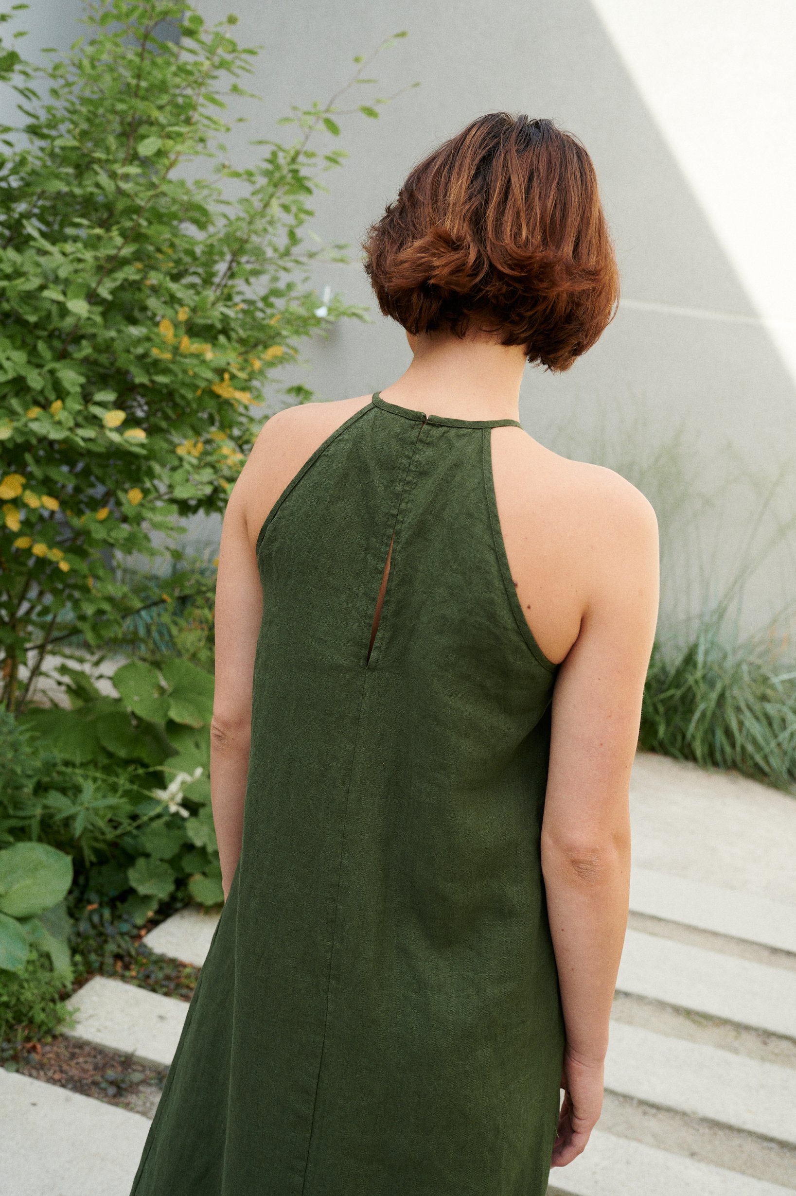 Back of a green linen dress with a halter neck and an eye closure