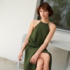 Woman sitting wearing a long green sleeveless linen dress