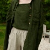 An oversized green waffle linen button down shirt with wooden buttons worn over a linen summer top and shorts