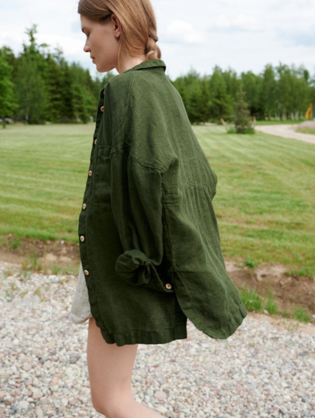 Model walking while wearing an oversized forest green waffle linen shirt