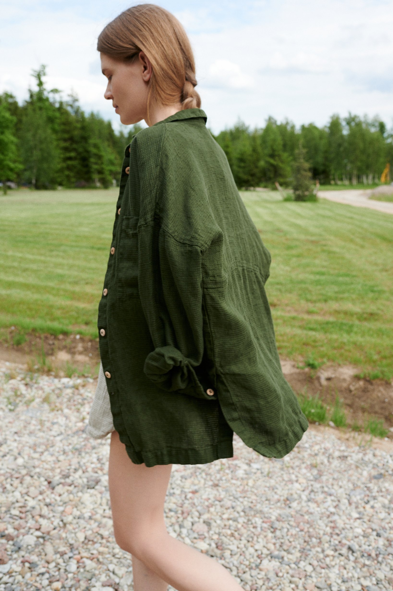 Model walking while wearing an oversized forest green waffle linen shirt