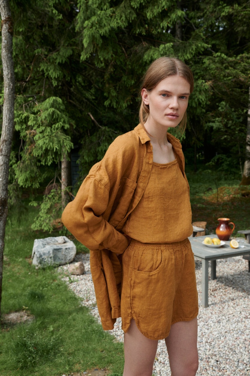 Woman in an oversized waffle linen shirt paired with matching linen summer top and shorts outfit