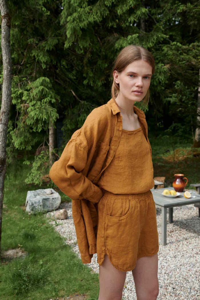 Woman wearing waffle linen shorts with a matching linen summer top and a button down shirt on top