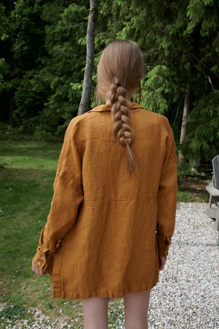 Back of a model in a loose fitting waffle-like textured linen shirt