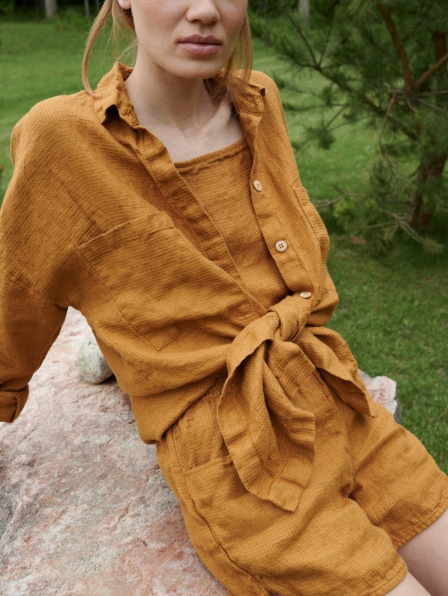 An oversized waffle-like textured linen button down shirt tied in the front