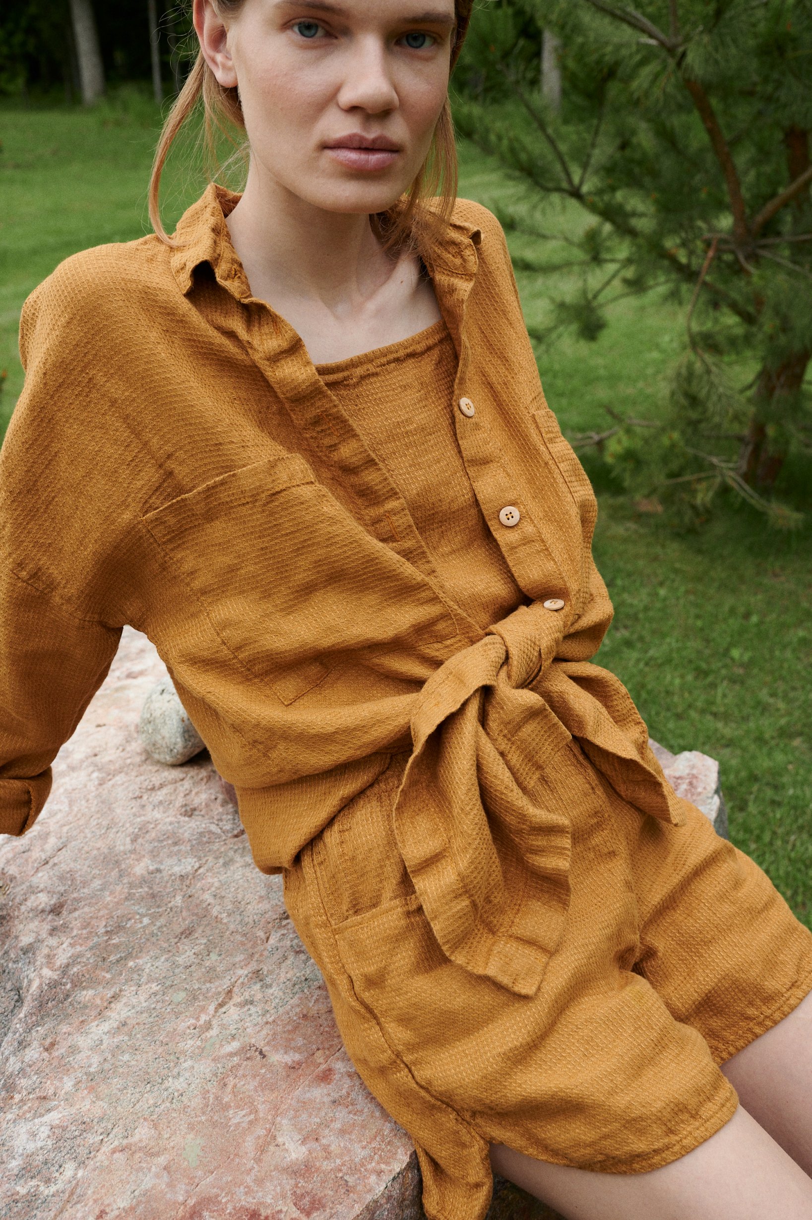 An oversized waffle-like textured linen button down shirt tied in the front
