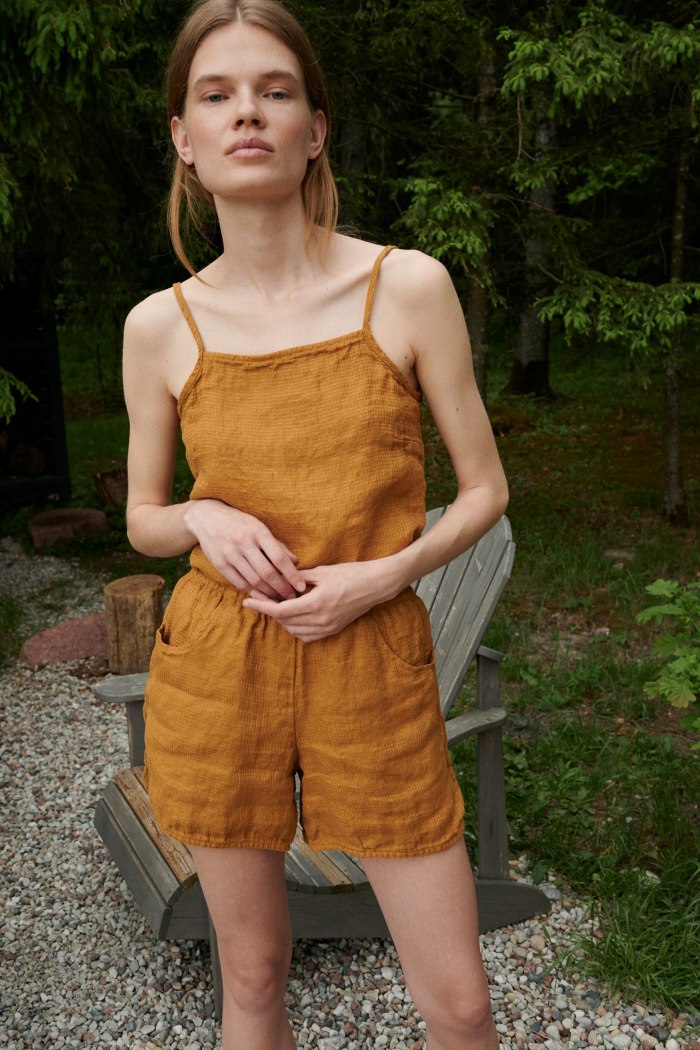 Woman wearing.a waffle linen summer top tucked into wide leg linen shorts
