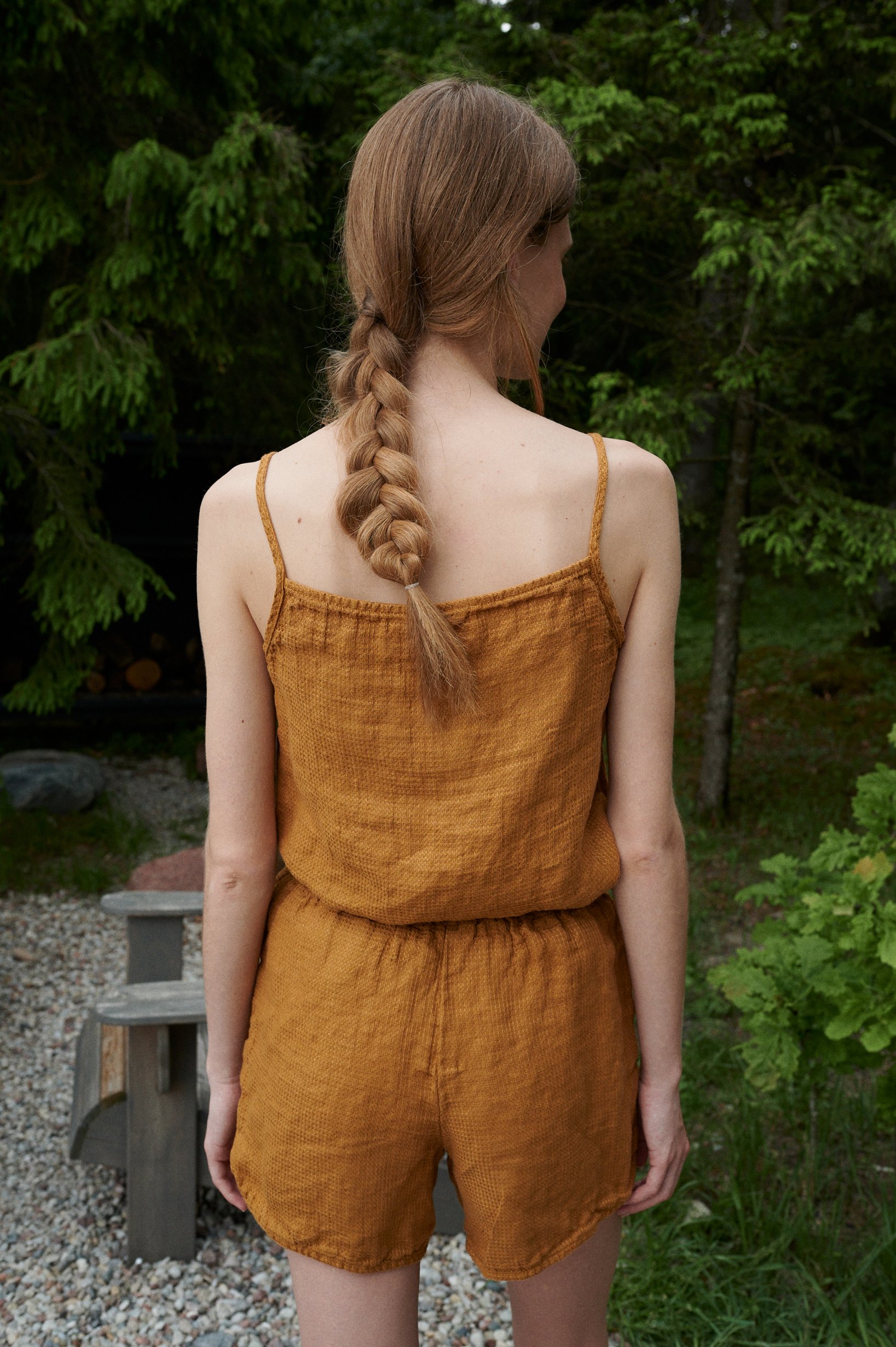 Back of a model in a waffle linen summer top with thin straps and matching linen shots with an elasticated waistband