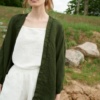 Woman wearing a green waffle linen jacket untied with a white linen summer top underneath