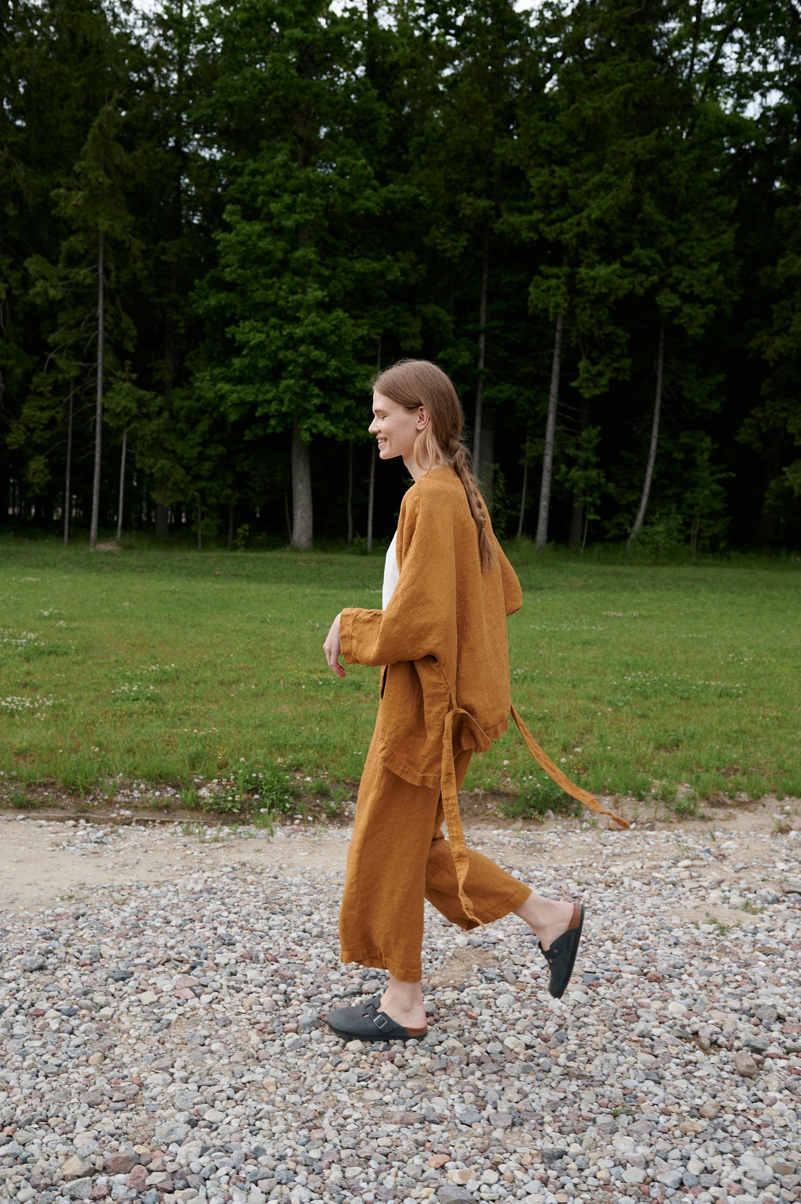 Woman walking while wearing a loose waffle-like textured linen jacket and cropped linen trousers