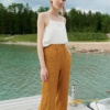 A woman standing in relaxed fit waffle linen trousers in camel