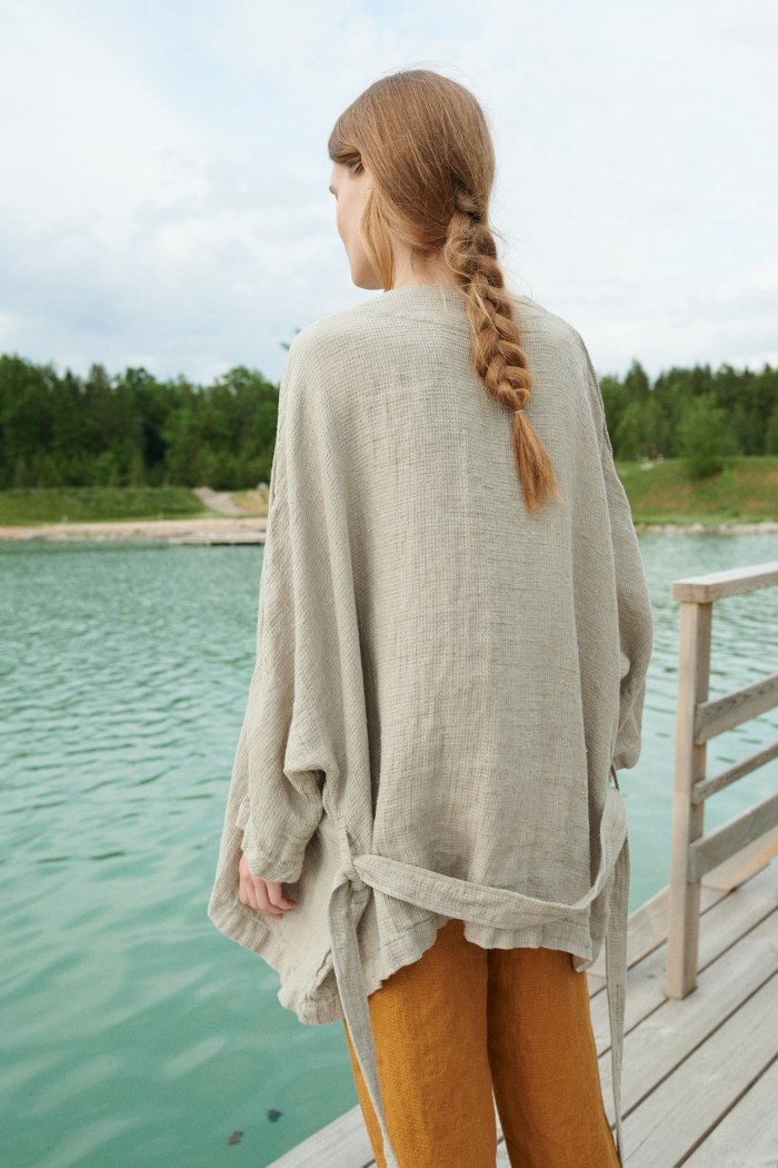 Back of a model in an oversized waffle linen wide sleeve jacket worn untied