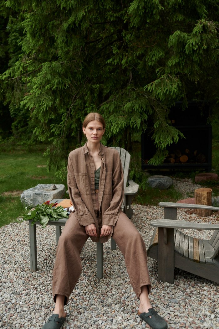 A model sitting in brown linen shirt with matching trousers