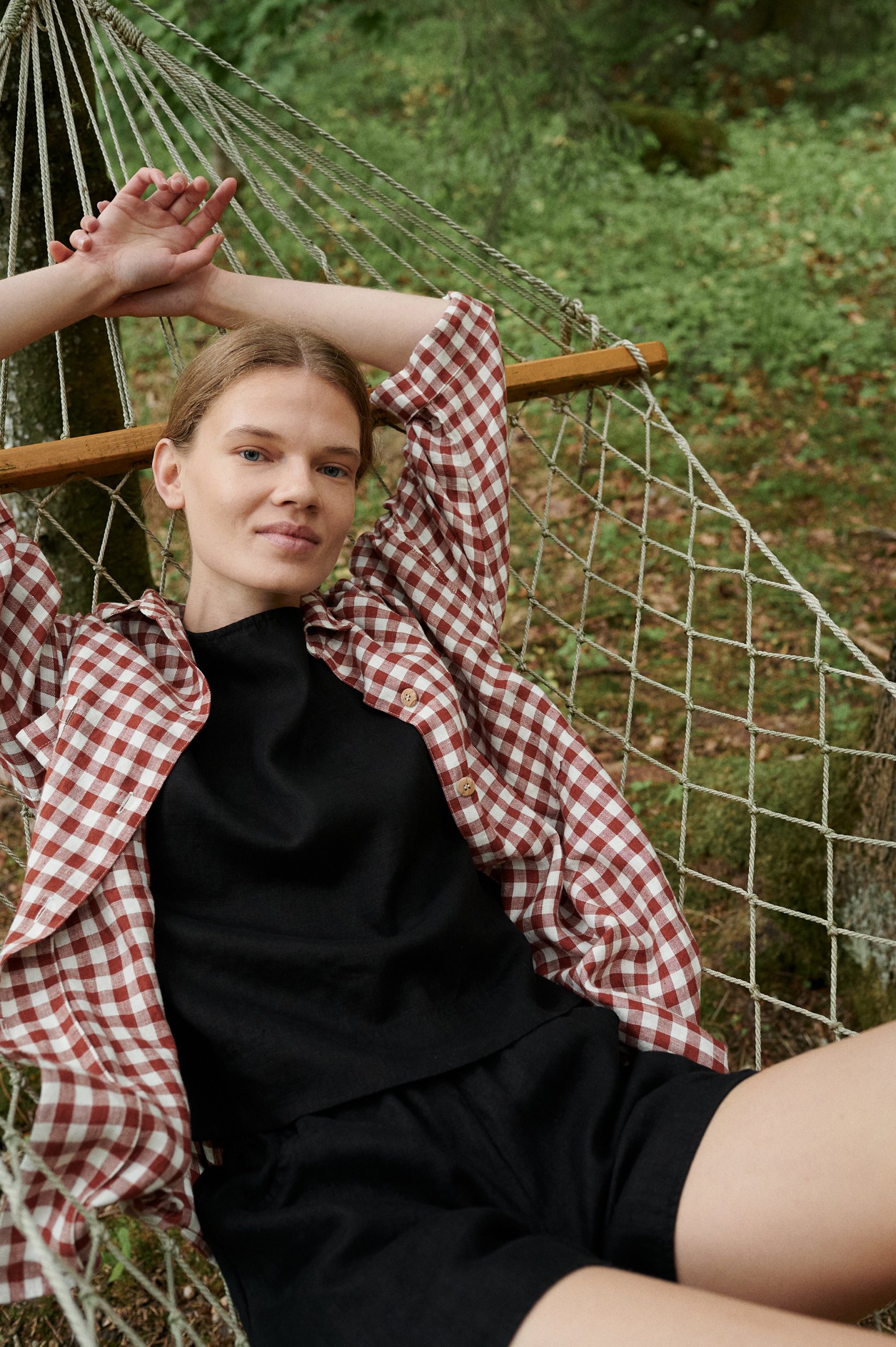 Model wearing a relaxed linen top and a terracotta gingham shirt on top