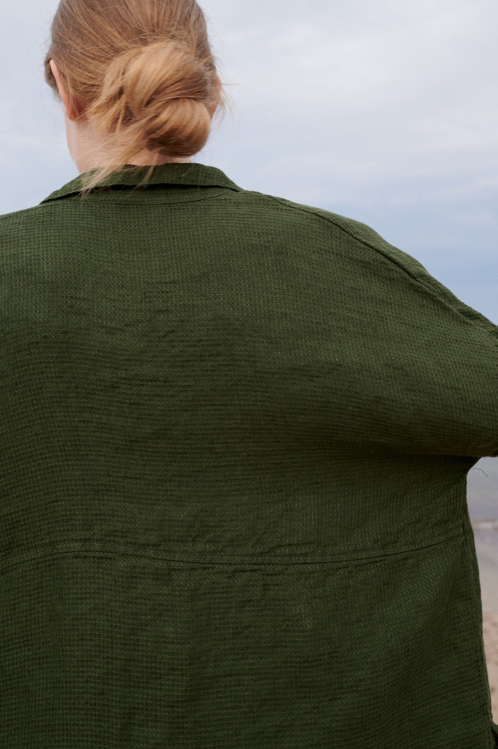 Back of a dark green loose-fitting waffle linen shirt