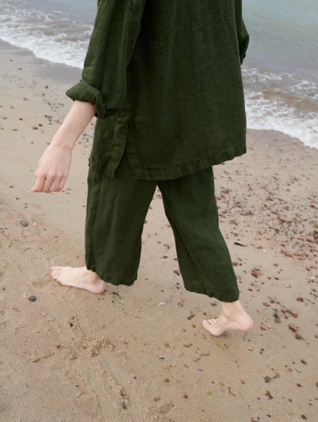 A woman wearing waffle linen wide leg trousers in dark green