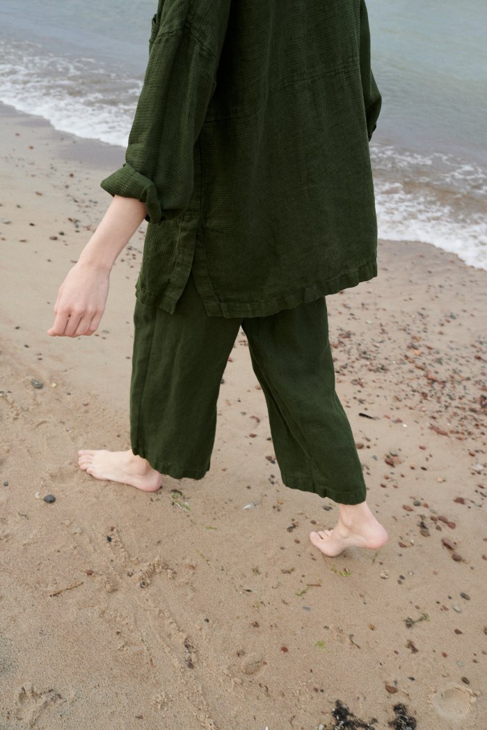 A woman wearing waffle linen wide leg trousers in dark green