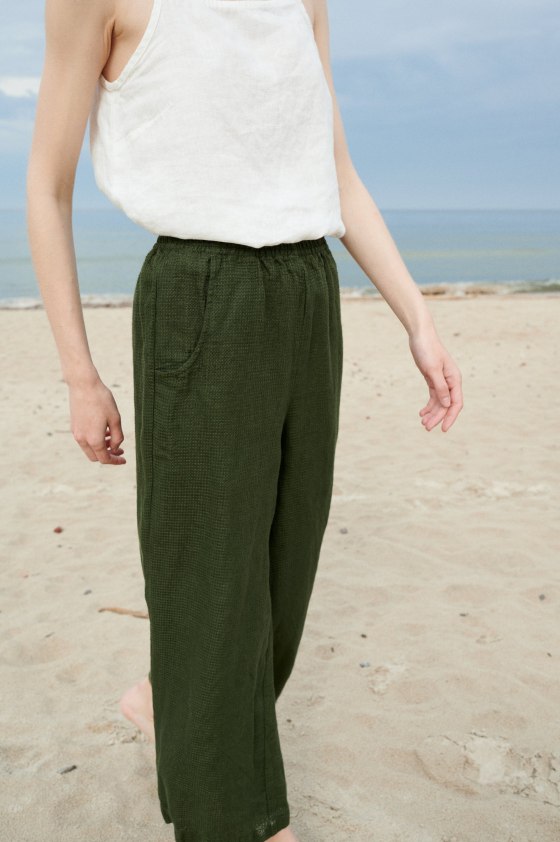 A woman wearing dark green wide leg trousers from waffle linen