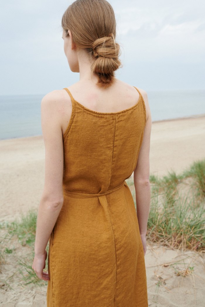Back of a woman wearing a dark yellow color waffle linen summer dress