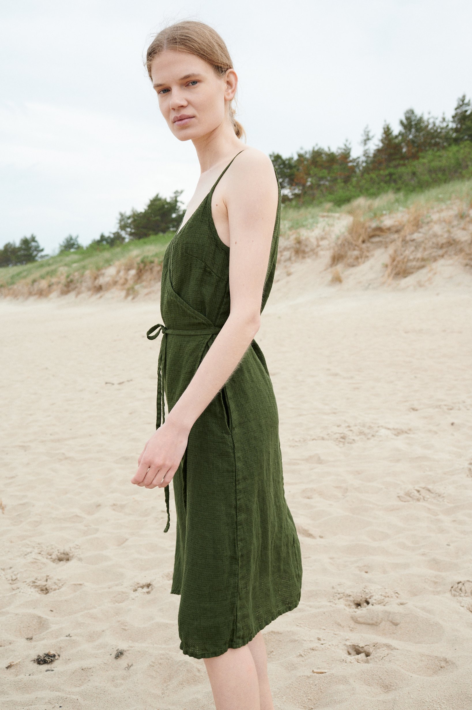 Side view of a waffle linen forest green summer dress with a belt