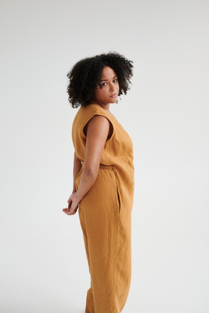 Side view of a model in an oversized linen jumpsuit with pockets
