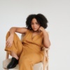 Model sitting in a camel linen jumpsuit with a wrap top part