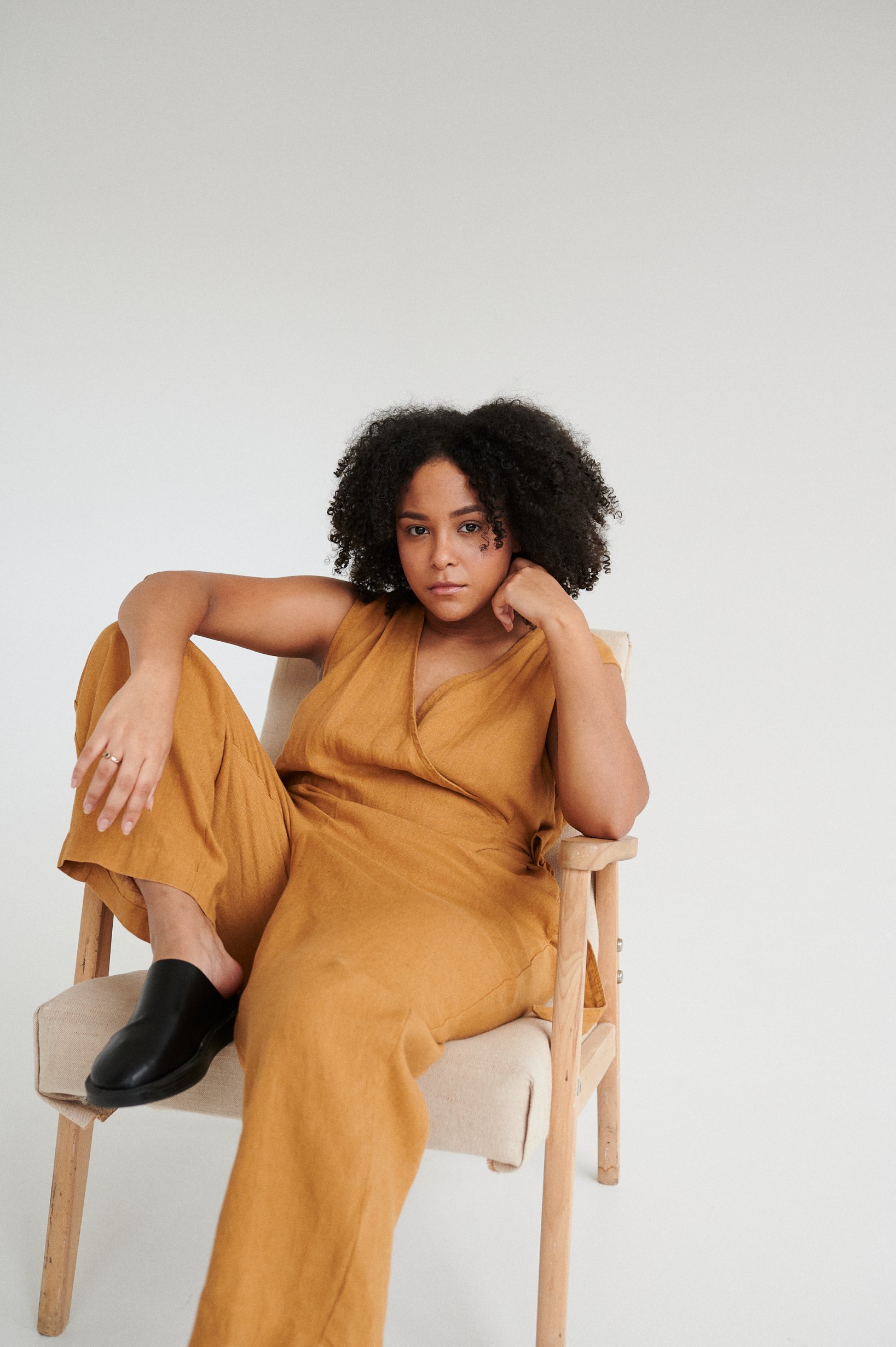Model sitting in a camel linen jumpsuit with a wrap top part
