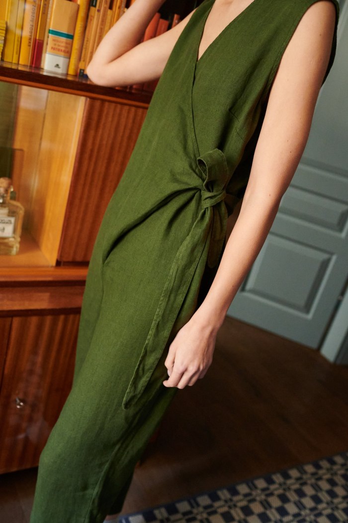 An oversized green linen jumpsuit with a belt tied on the side