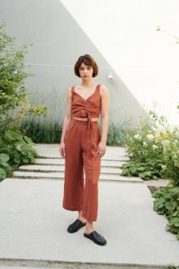 Model in a sleeveless wrap linen top and high-waisted linen trousers