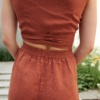An elasticated waistband of terracotta linen trousers and a cropped linen top