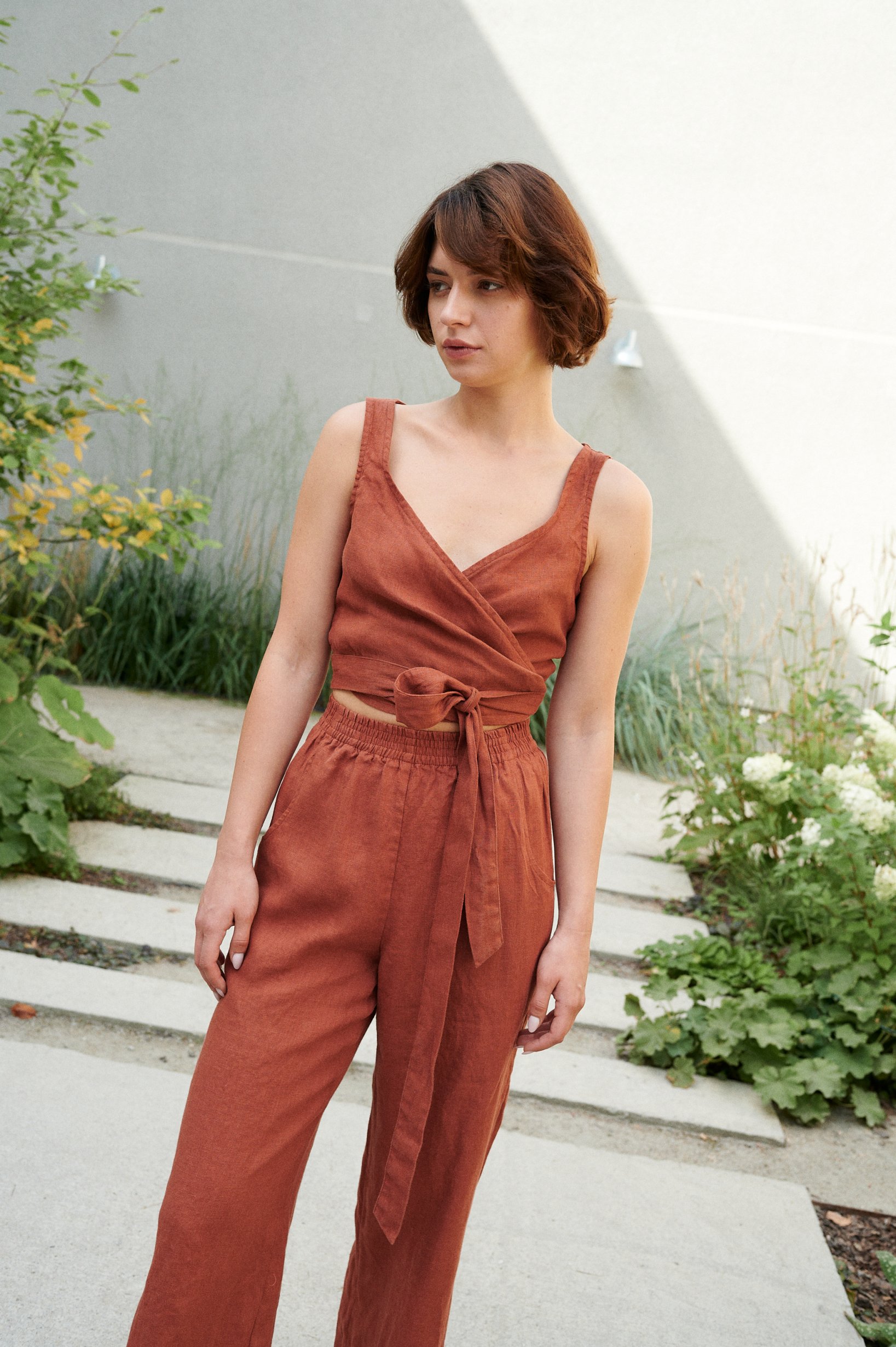 Model wearing a terracotta cropped linen top with matching high-waisted linen trousers