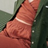 Details of a terracotta wrap linen top and an elasticated waist of linen trousers