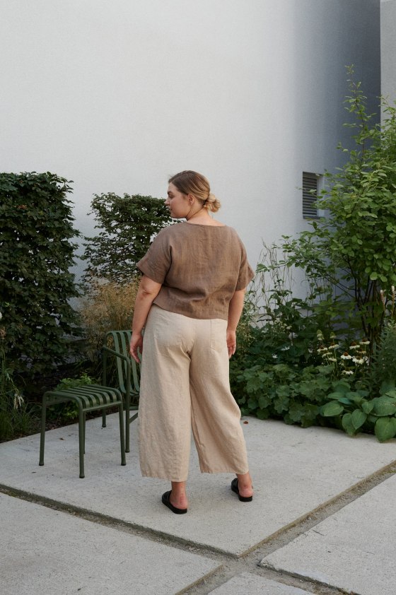 Woman's back wearing beige linen barrel trousers