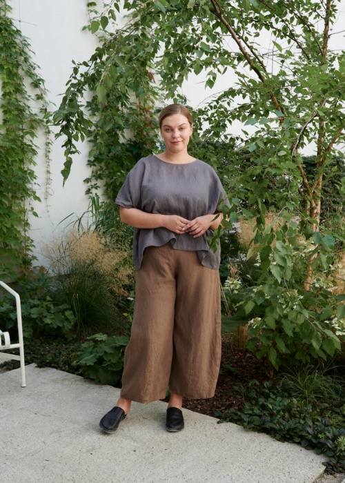 A woman standing in brown natural linen trousers in brown