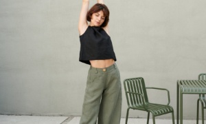 A woman stretching in heavy linen barrel trousers in green