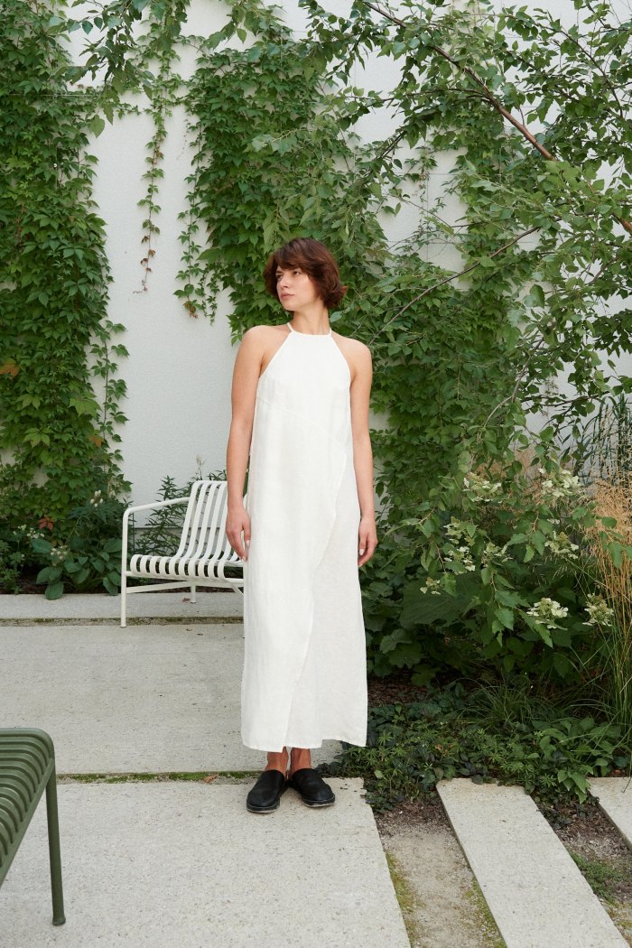 Model wearing a milky white linen dress with an asymmetrical seam