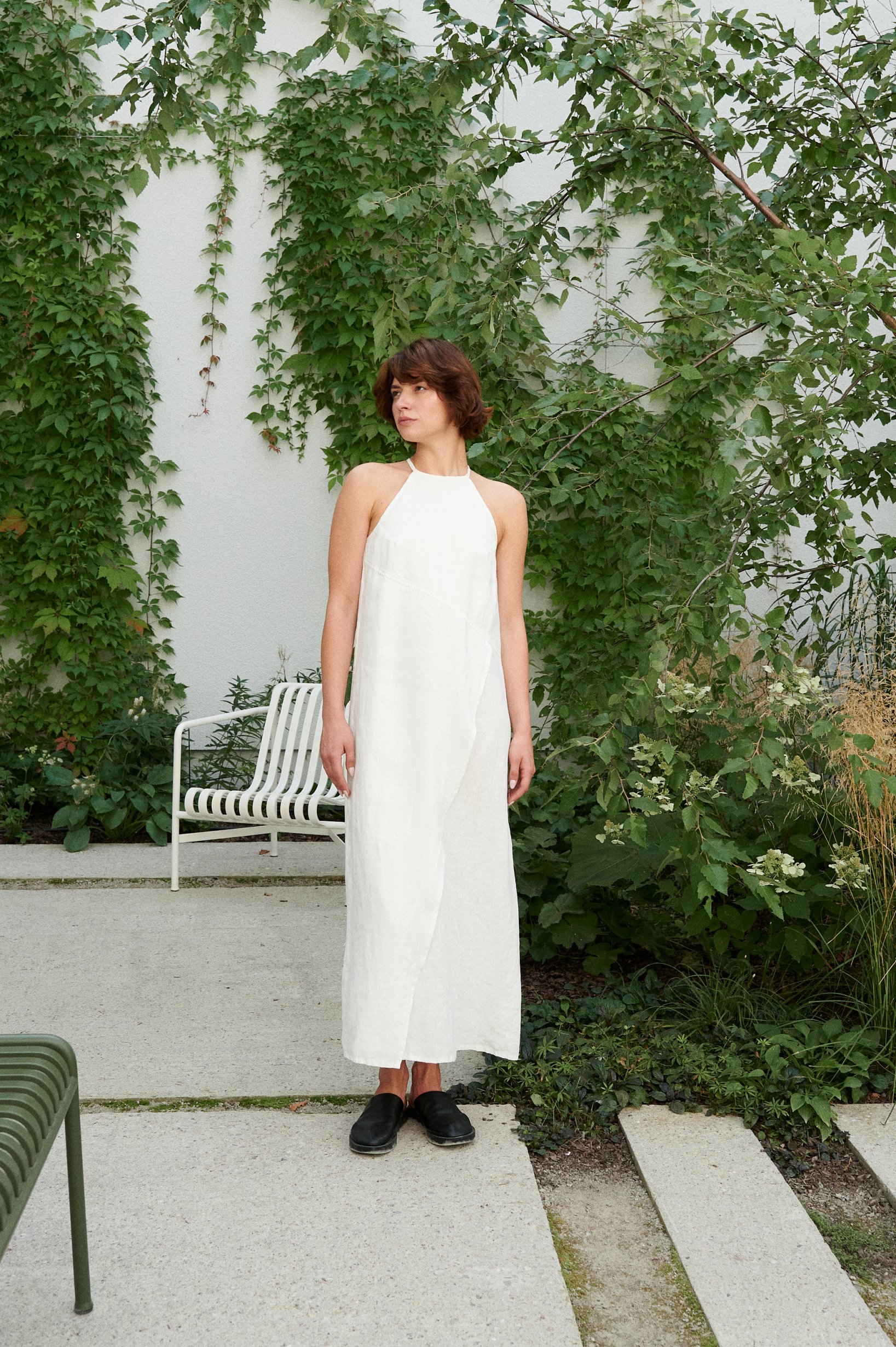 Model wearing a milky white linen dress with an asymmetrical seam