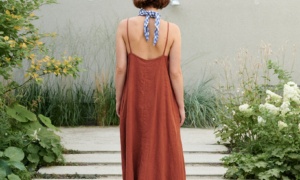 Back of a model wearing a long linen summer dress with a low-cut back and thin straps