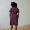 Back of a model wearing a purple wrap linen dress wrapped with ties around the waist