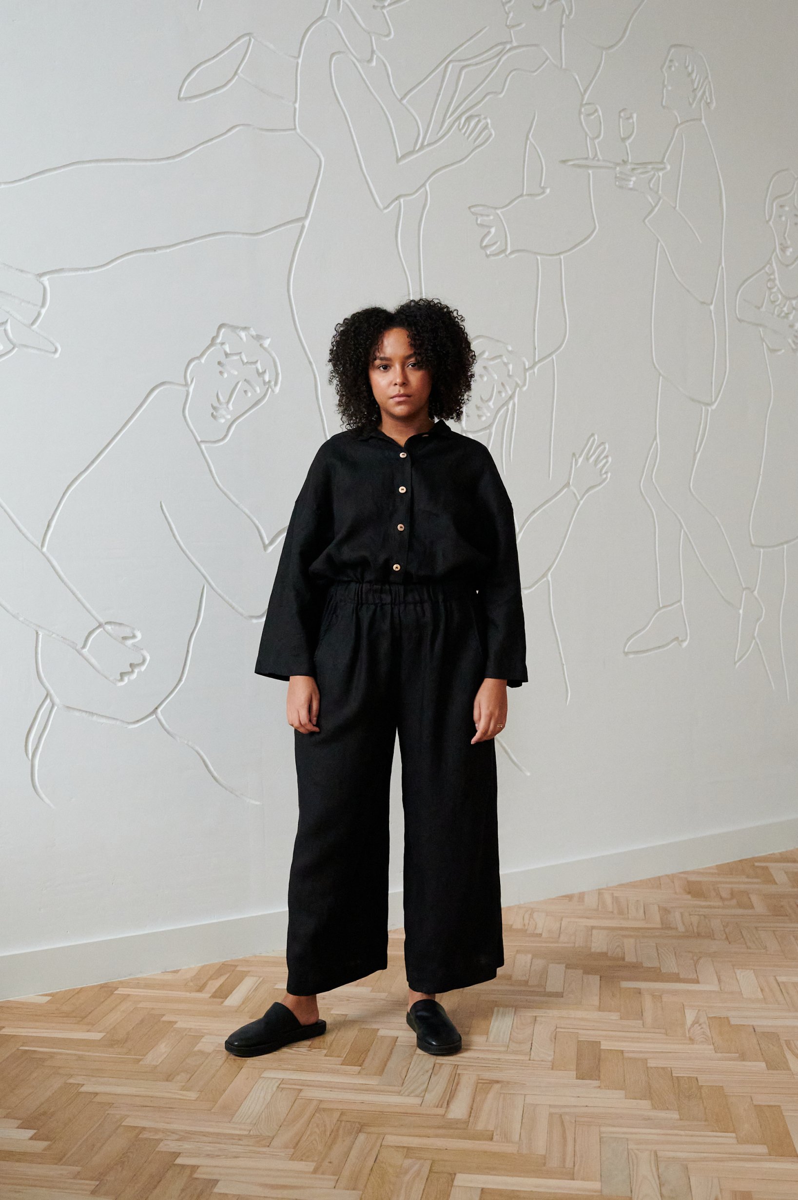 A woman in a room, wearing matching black linen shirt and pants