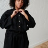 A woman buttoning up linen shirt in black