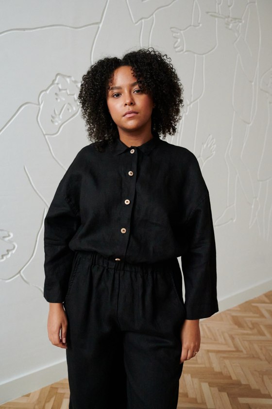 A woman standing in black linen button up shirt