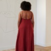 Back of a model wearing a red flared maxi linen dress with a low-cut back and spaghetti straps